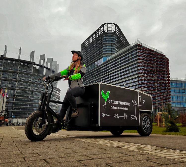 jeune femme au volant d'un vélo cargo devant le parlement européen 